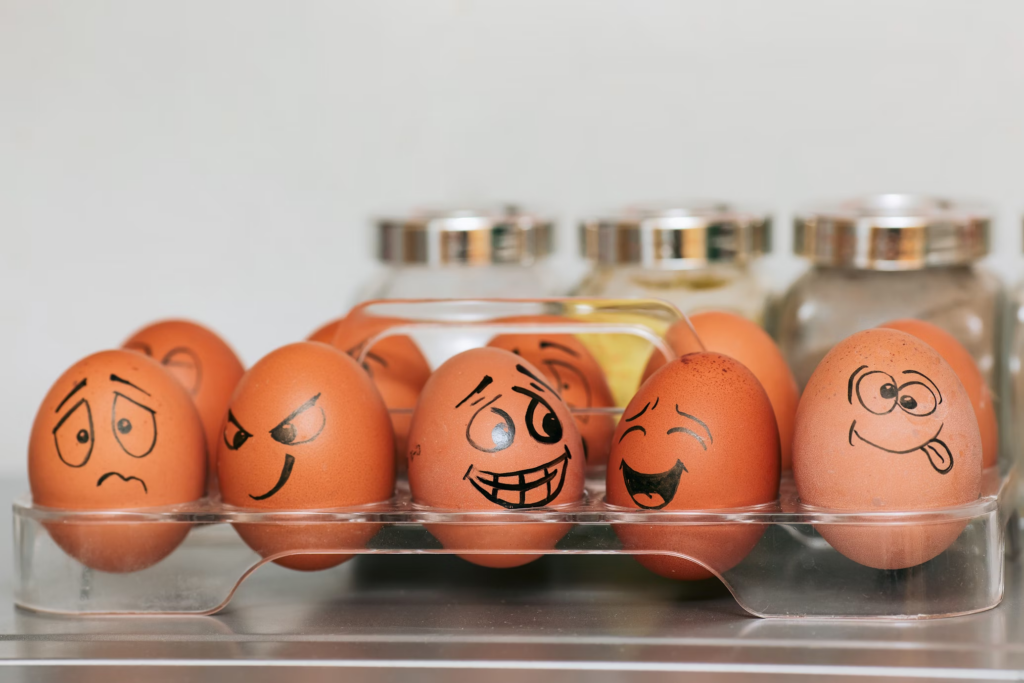 A row of five brown eggs with various comical faces drawn on them